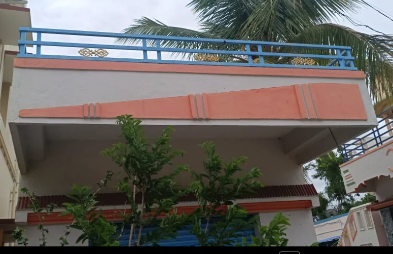 House frontage with a broad coral canopy, roof terrace and blue-grey decorative railings.